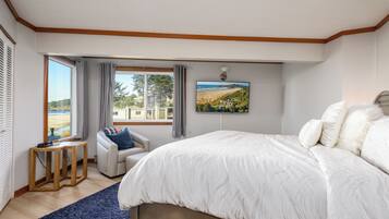 Ein Schlafzimmer mit einem großen Bett, Meerblick, einem kleinen Tisch und einem Stuhl.