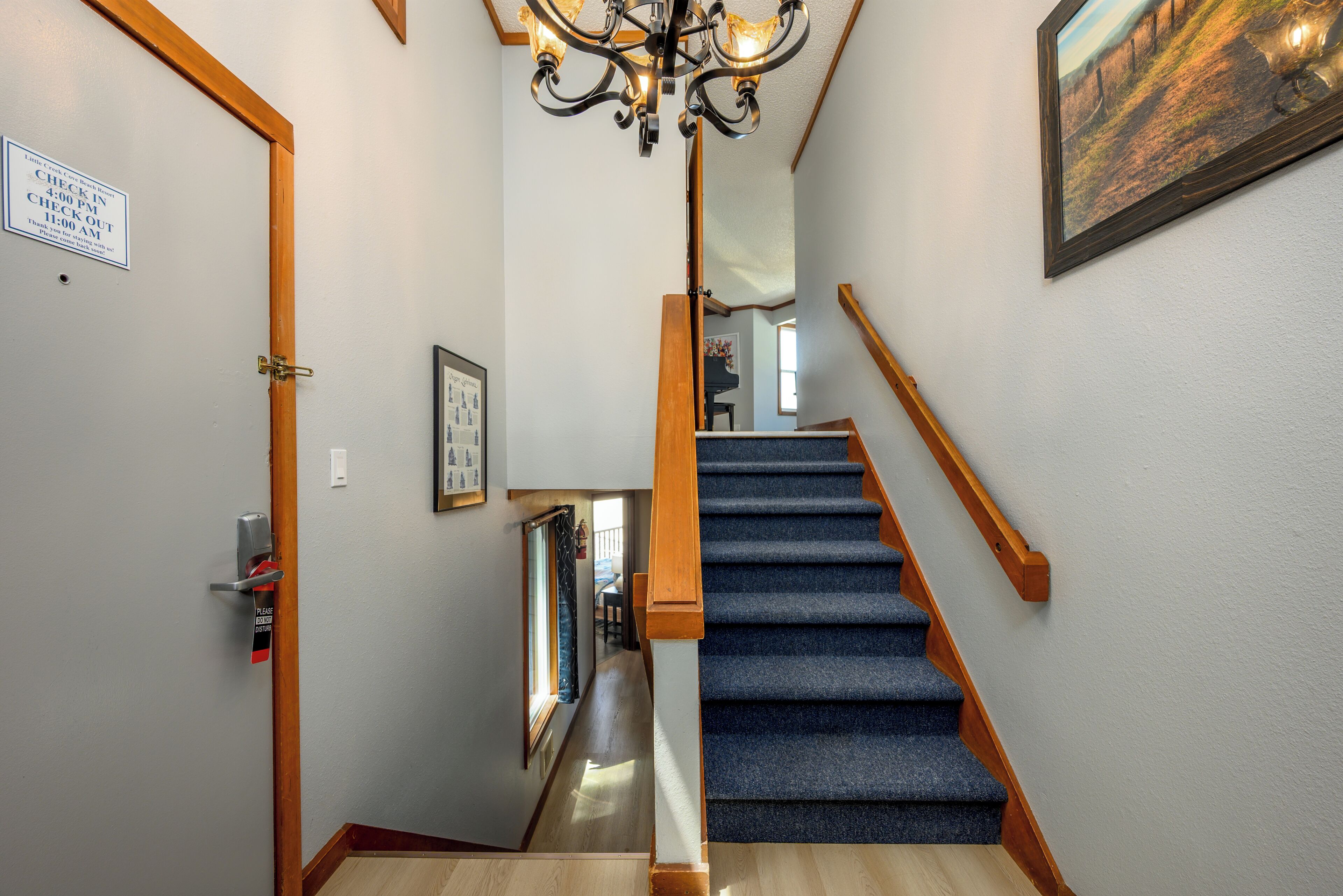 Un escalier recouvert d’une moquette bleue et doté de rampes en bois, menant à l’étage supérieur.