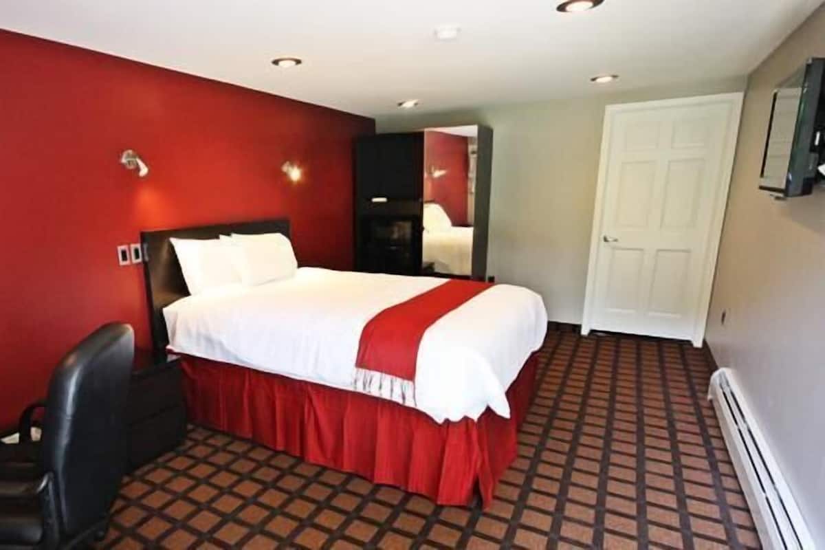 A hotel room with a bed, a desk, and a chair.