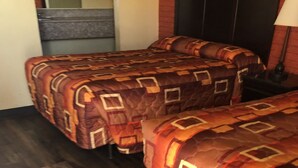 Une chambre d’hôtel avec deux lits, un plancher en bois et une table de chevet avec une lampe.