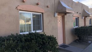 Un bâtiment à l’extérieur beige, avec une porte portant le numéro « 52 » et une fenêtre dotée d’un cadre blanc.