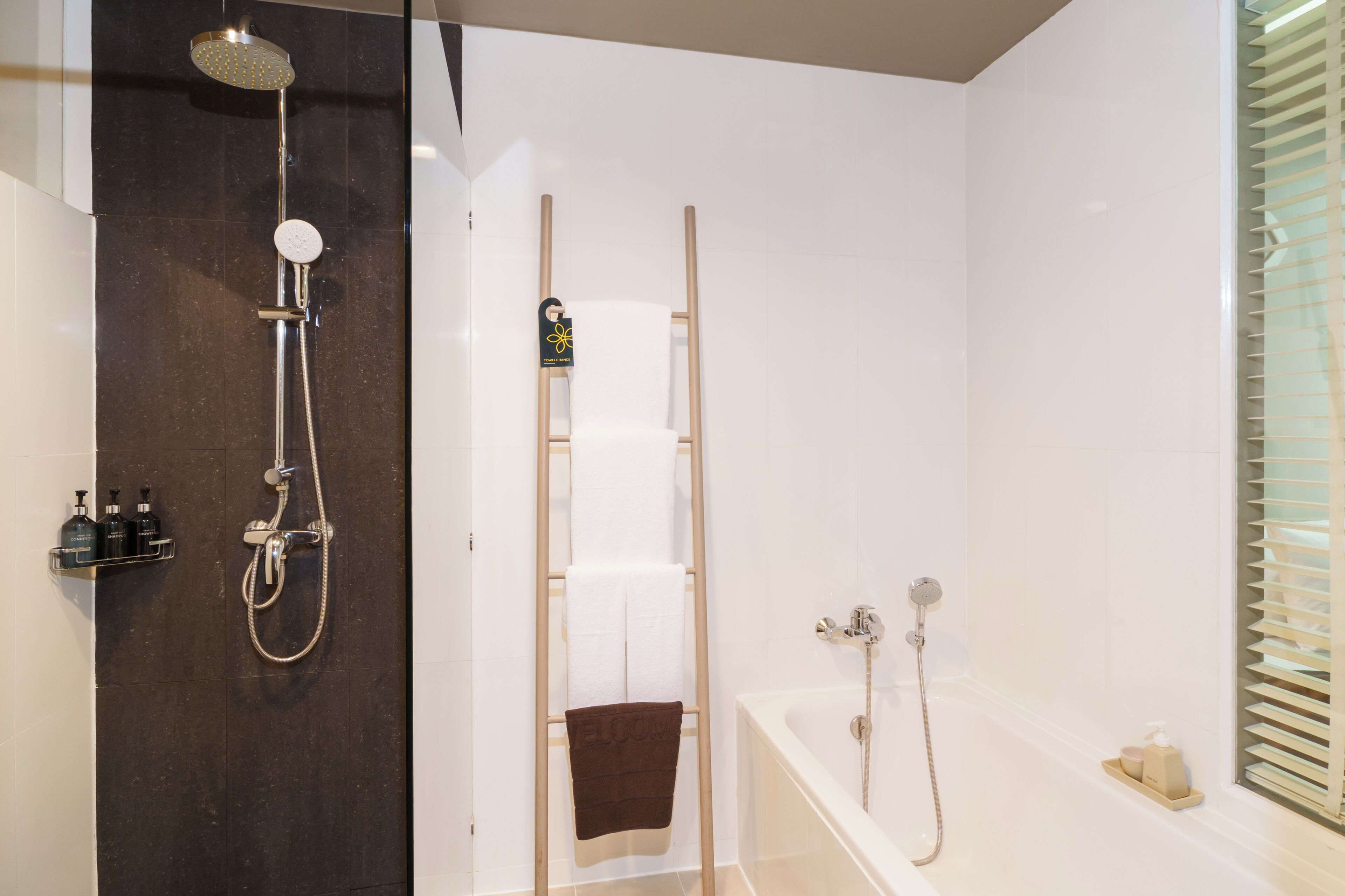 A modern bathroom with a shower, a bathtub, and a towel rack.
