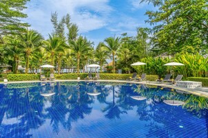 A clear blue pool surrounded by palm trees and lounge chairs.