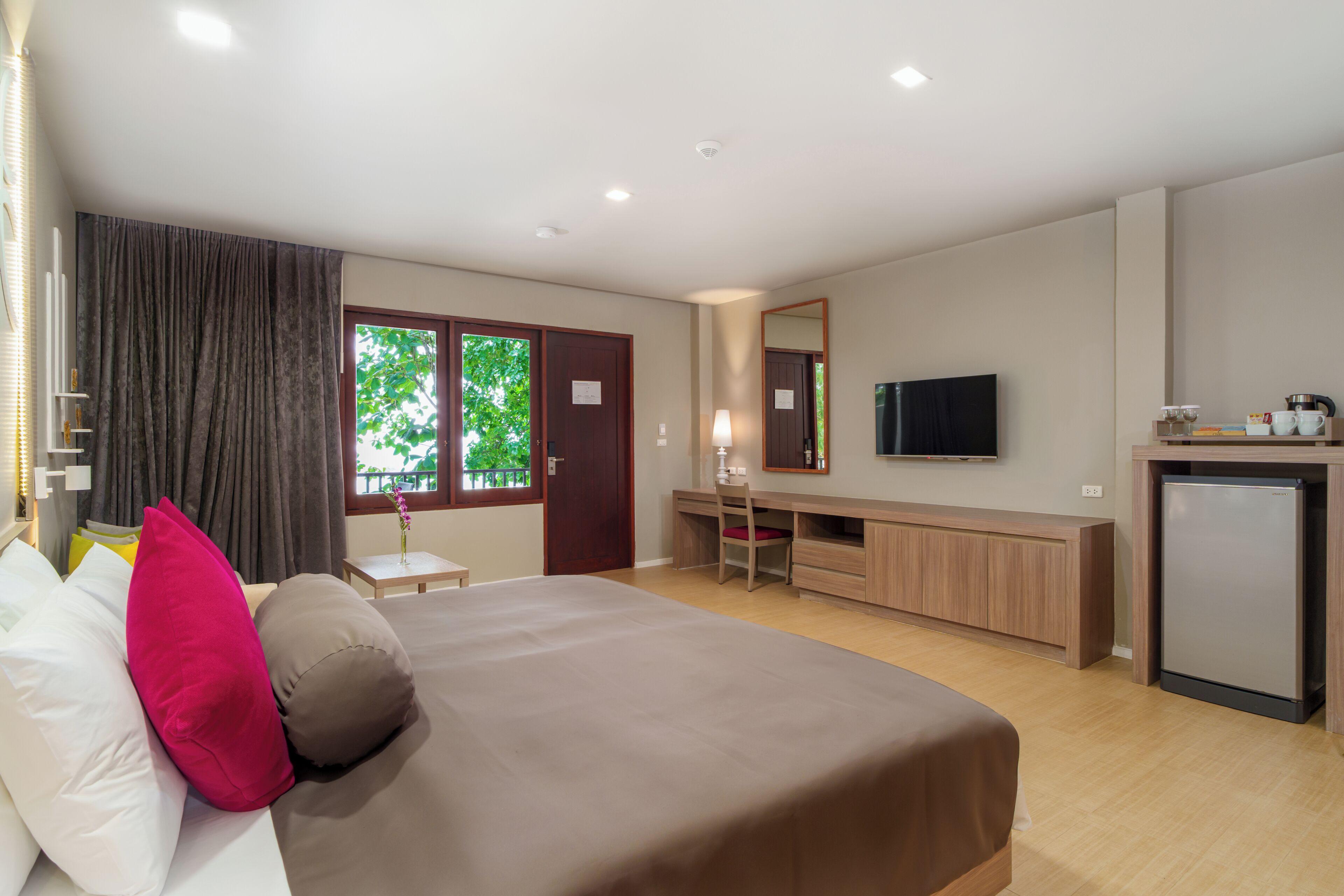 A hotel room with a bed, desk, chair, television, and a small refrigerator.