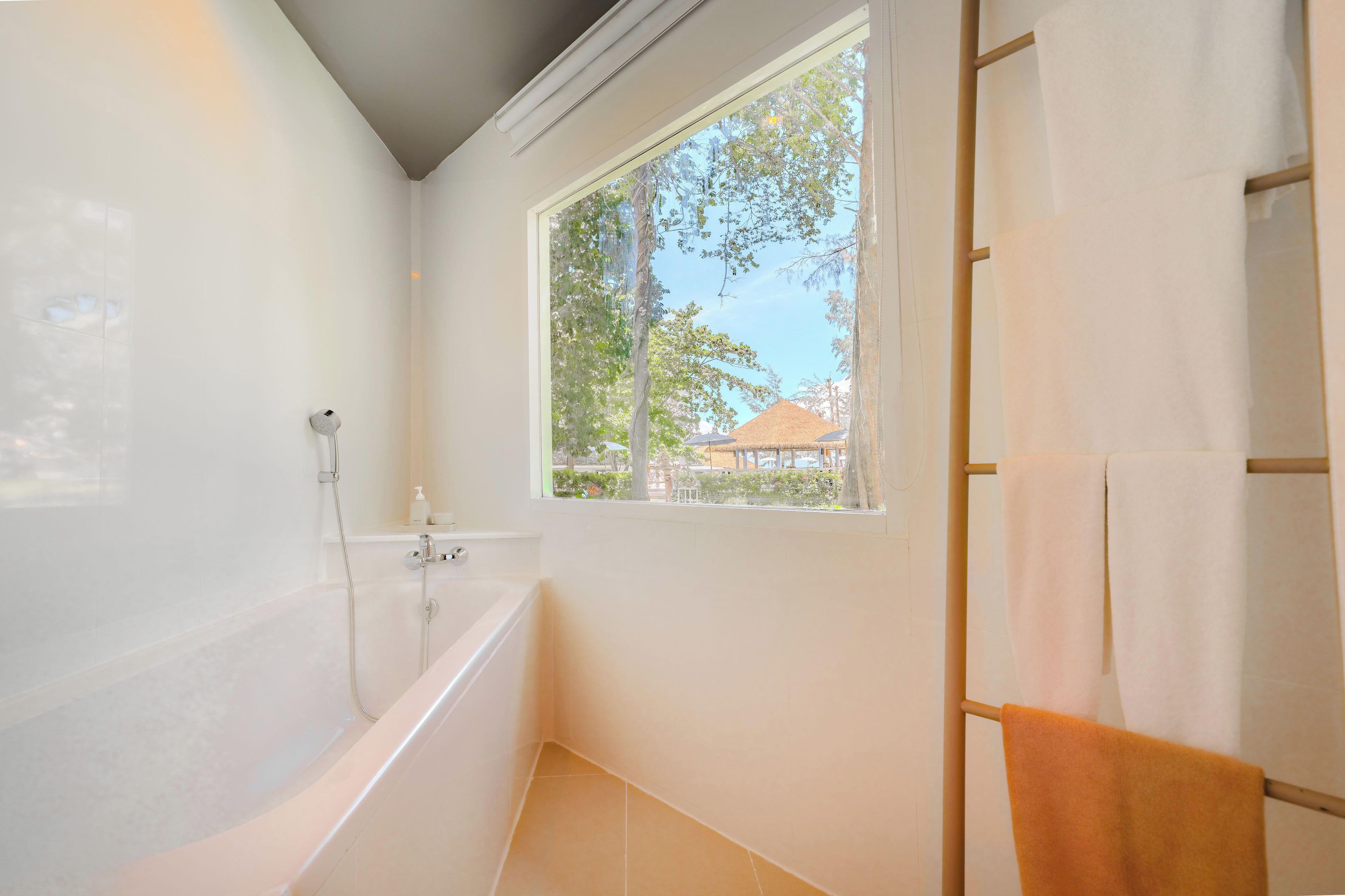 A bathroom with a bathtub, a window, and a towel rack.