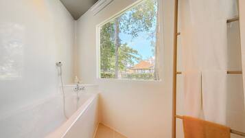 A bathroom with a bathtub, a window, and a towel rack.
