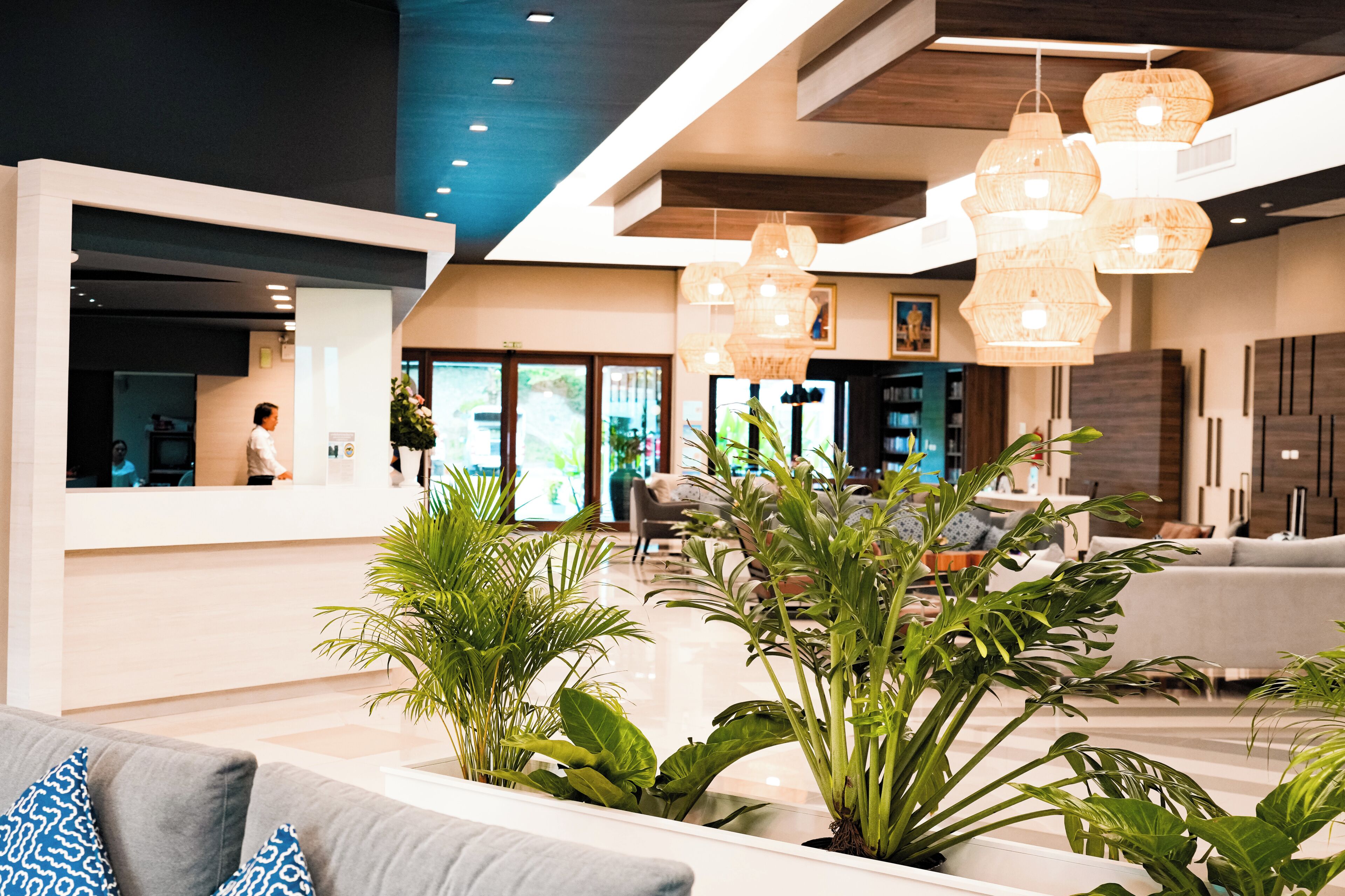 Eine moderne Lobby mit einer Rezeption, einer Sitzecke und hängenden Pendelleuchten.