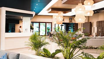 Eine moderne Lobby mit einer Rezeption, einer Sitzecke und hängenden Pendelleuchten.