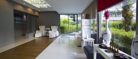 A modern spa area with white furniture, a glass ceiling, and a view of greenery outside.