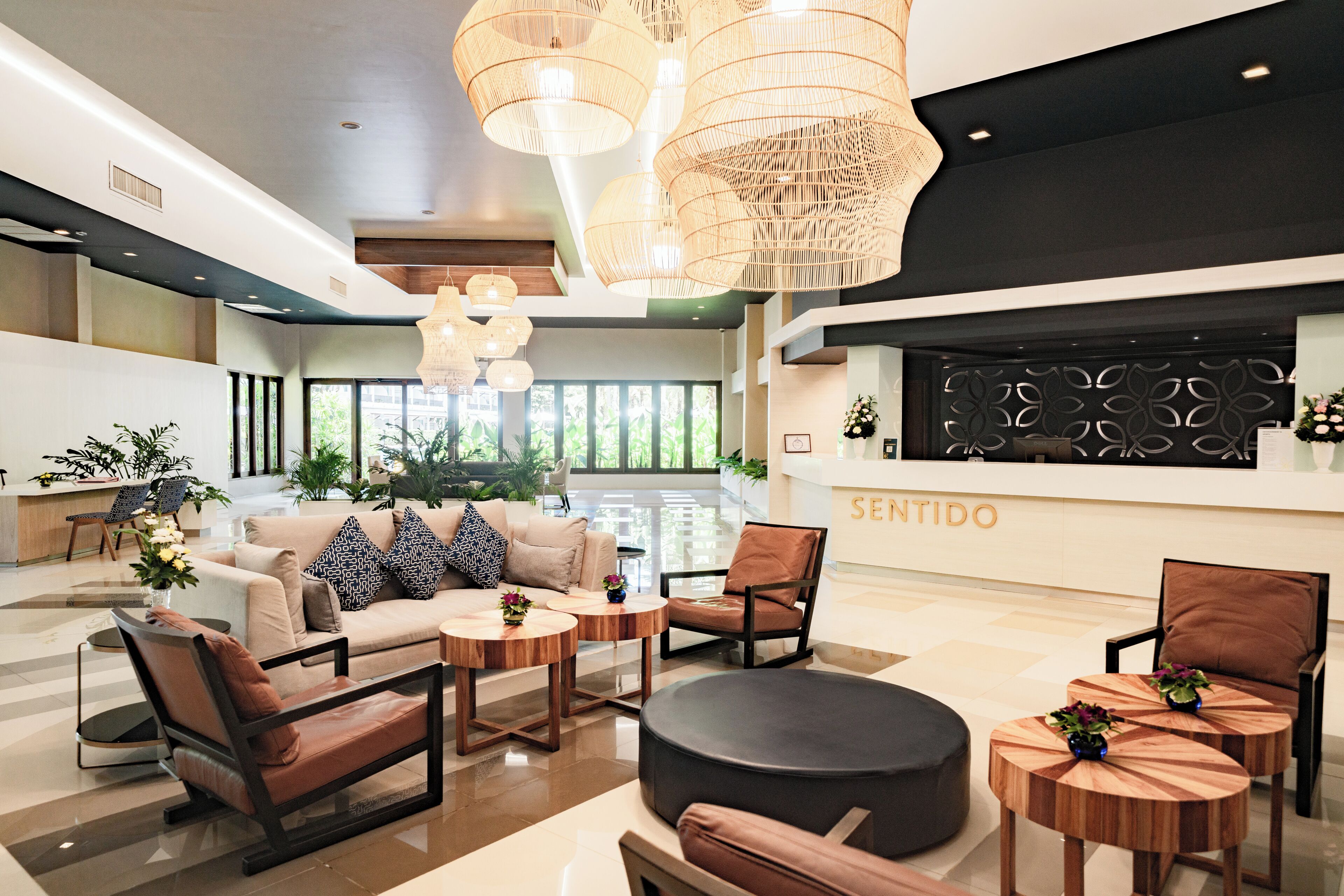 A modern lobby with a reception desk, seating area, and large windows.