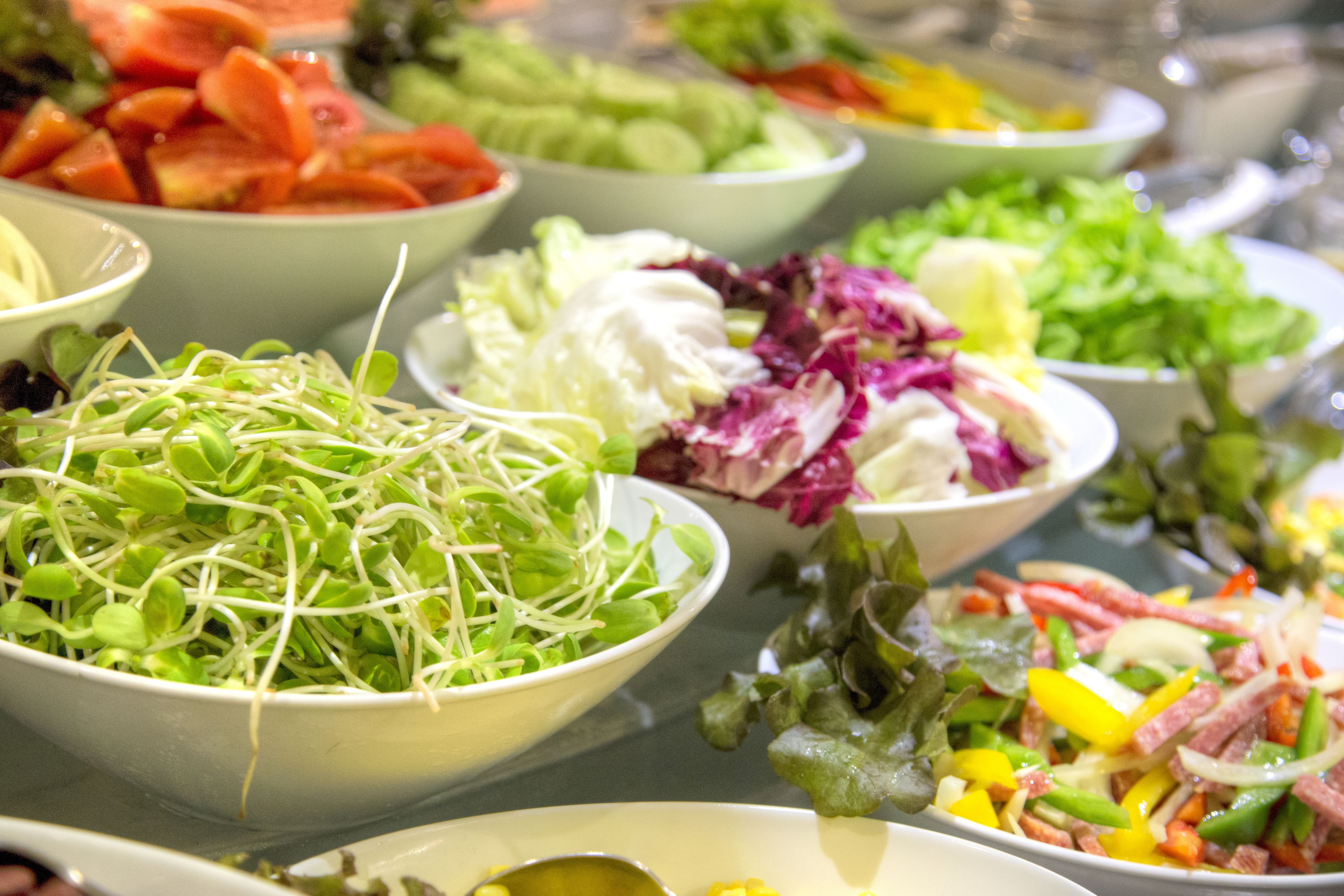 A variety of salad bowls with different vegetables.