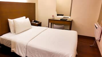 Une chambre d’hôtel équipée d’un lit, d’un bureau, d’un téléphone et d’un miroir.