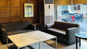 Un interior modern amb un sostre de fusta, dues làmpades penjants, un aparell d'aire condicionat gran i una zona de seients amb sofàs i una taula de centre de vidre.
