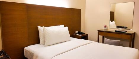 A hotel room with a bed, a nightstand, a desk, and a mirror.
