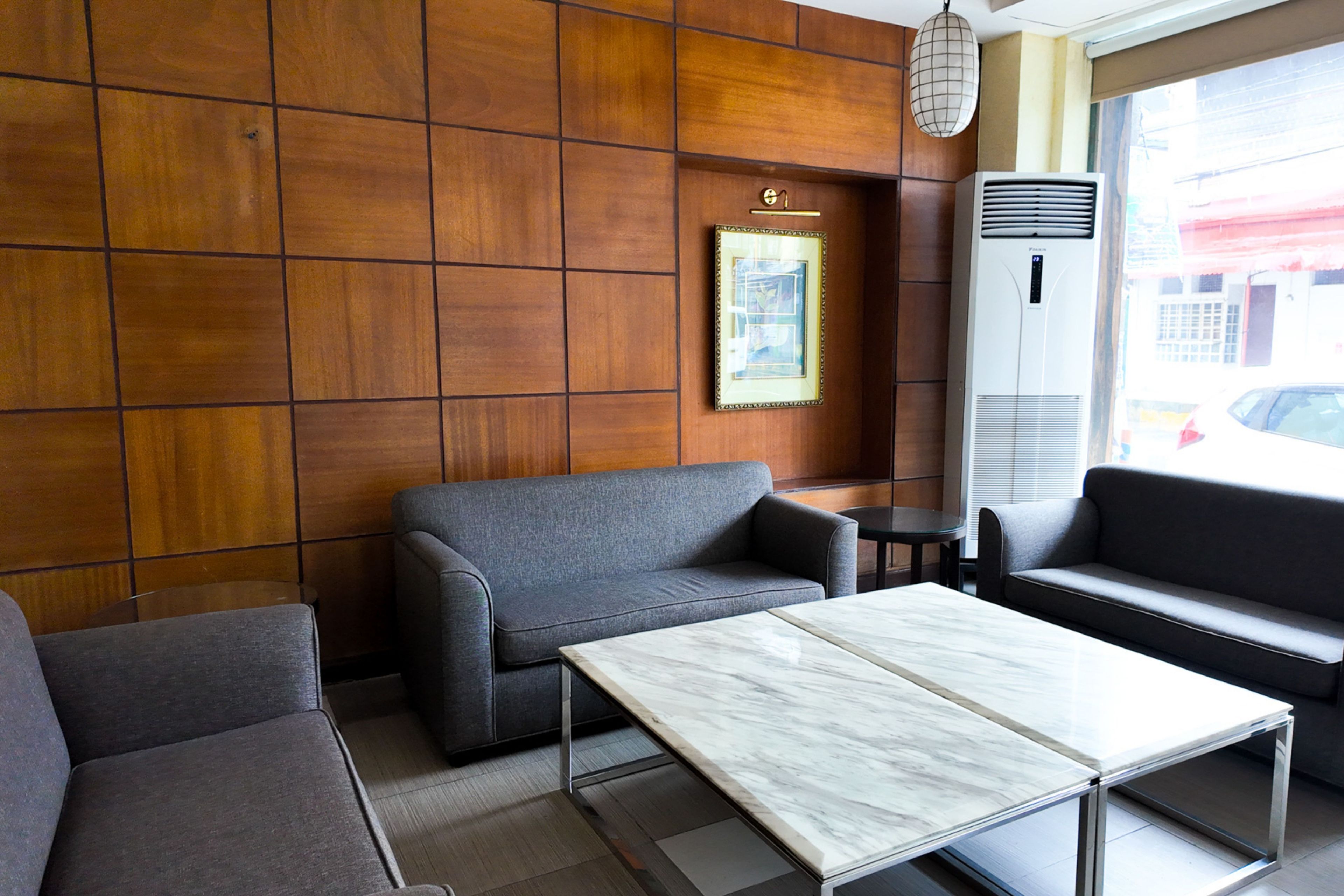 A modern interior with a grey sofa, a marble table, and a wall-mounted air conditioner.