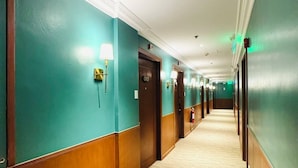 A hotel hallway with teal walls, wooden paneling, and carpeted floors. - Pearl Lane Hotel (Manila)