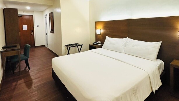 Una habitació d'hotel amb un llit gran, una taula de treball, una cadira i una taula petita.