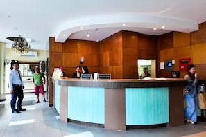 A hotel reception area with a curved reception desk, a chandelier, and a security camera. - Pearl Lane Hotel (Manila)