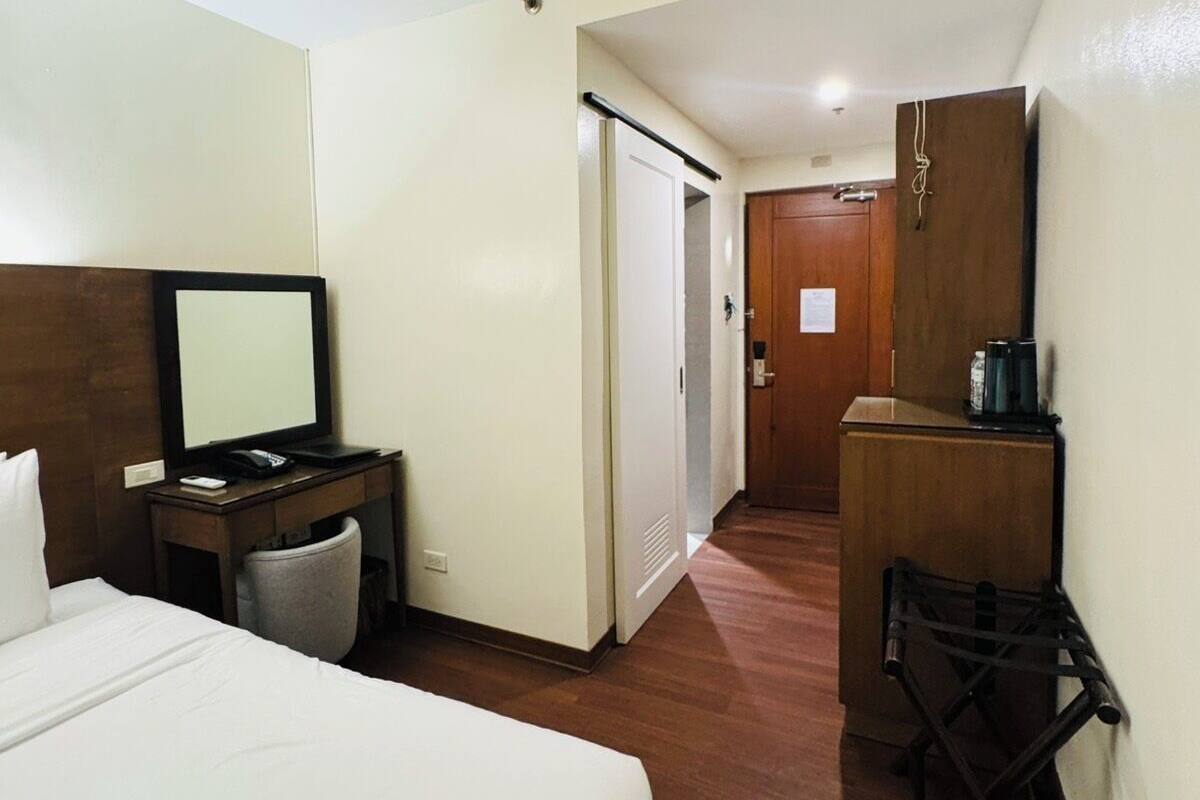 Habitación de hotel con cama, escritorio, silla, armario y una pequeña cocina.