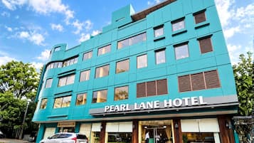 A hotel with a modern turquoise facade, multiple windows, and a visible entrance.