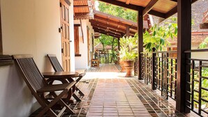 A covered outdoor area with a tiled floor, wooden furniture, and potted plants. - Reuan Thai Village Samui (Koh Samui)