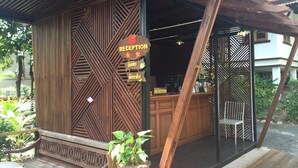 A reception area with a wooden facade, a reception desk, and a bench. - Reuan Thai Village Samui (Koh Samui)