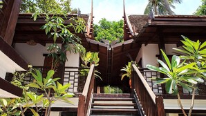 A wooden staircase with a traditional design, surrounded by lush greenery and a clear sky. - Reuan Thai Village Samui (Koh Samui)