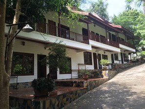 A two-story building with a balcony, stone steps, and potted plants. - Reuan Thai Village Samui (Koh Samui)