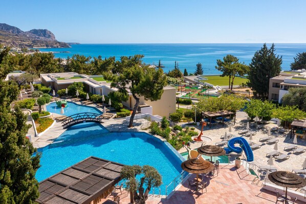 Un complejo turístico con una amplia piscina, un puente y vistas al mar.