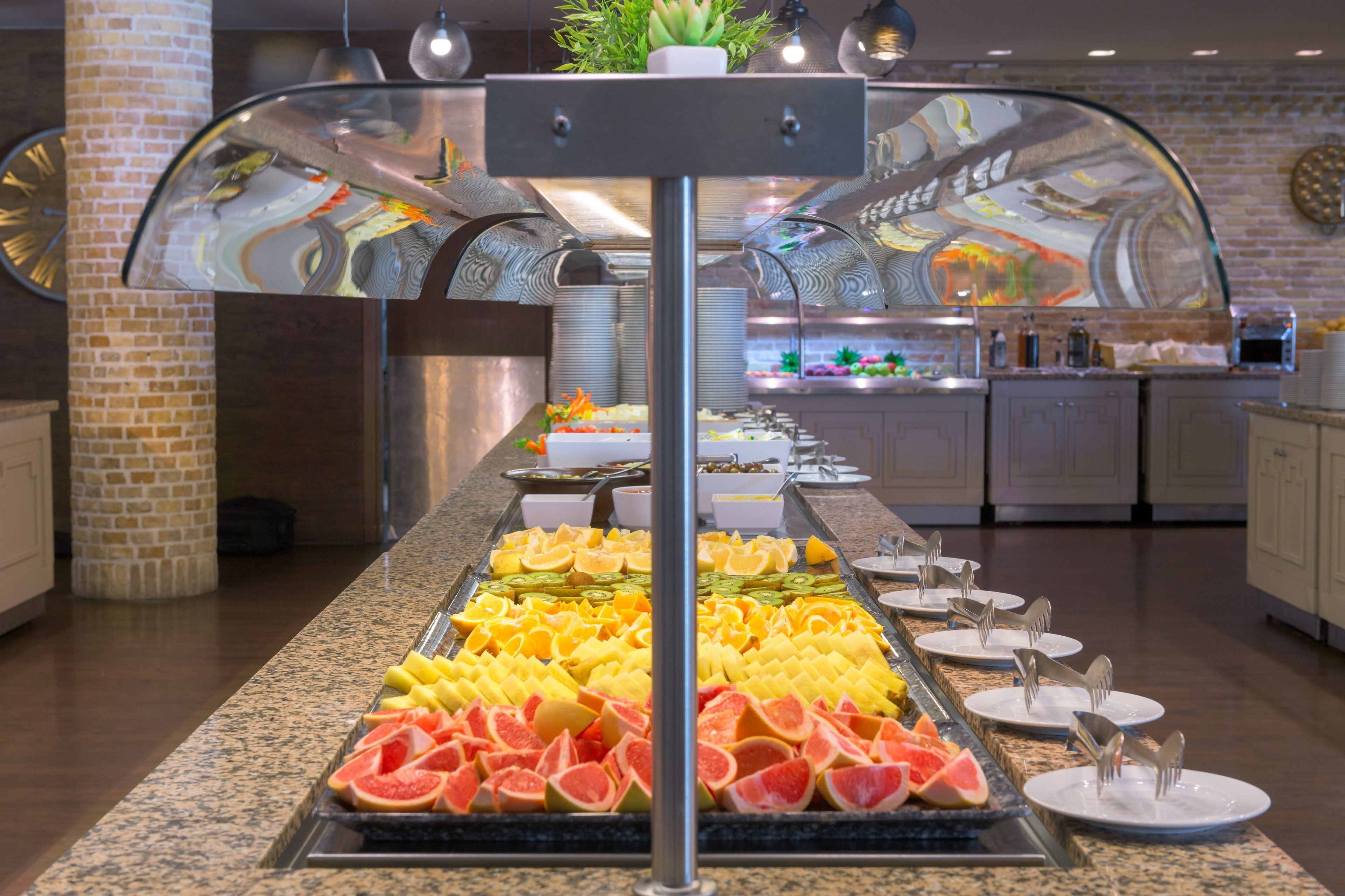 A buffet with various fruits and a glass enclosure.