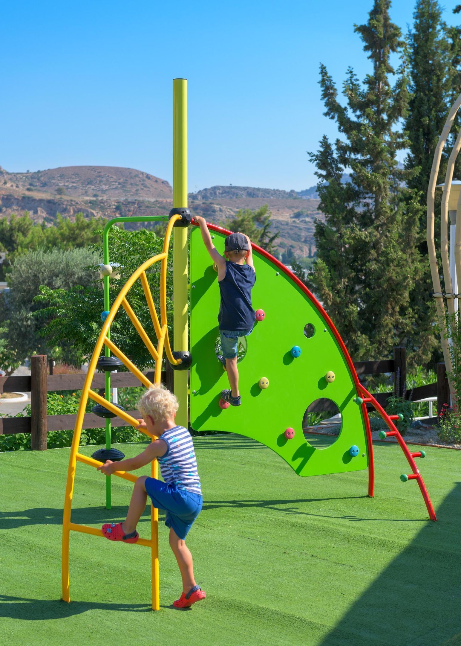 Un parque infantil con estructuras para escalar y una zona verde.