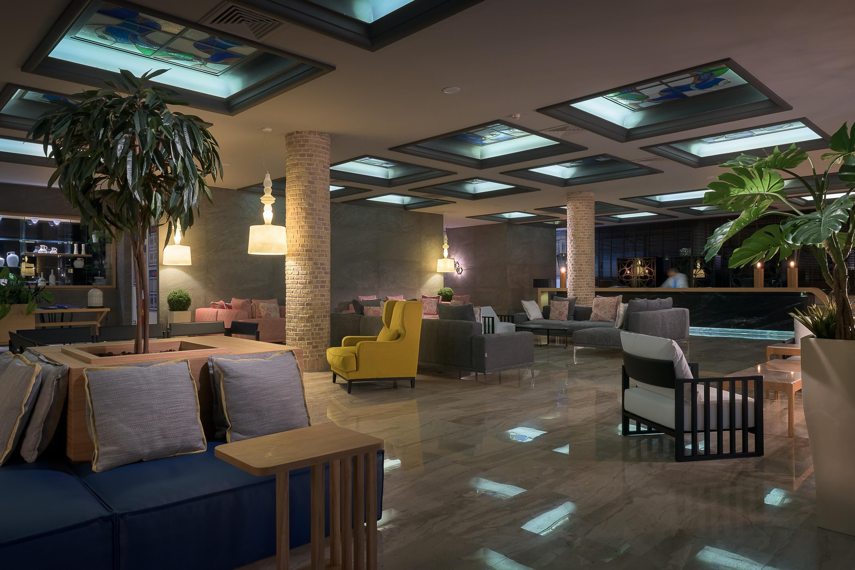 A spacious lobby with modern furniture, a large plant, and a bar area.