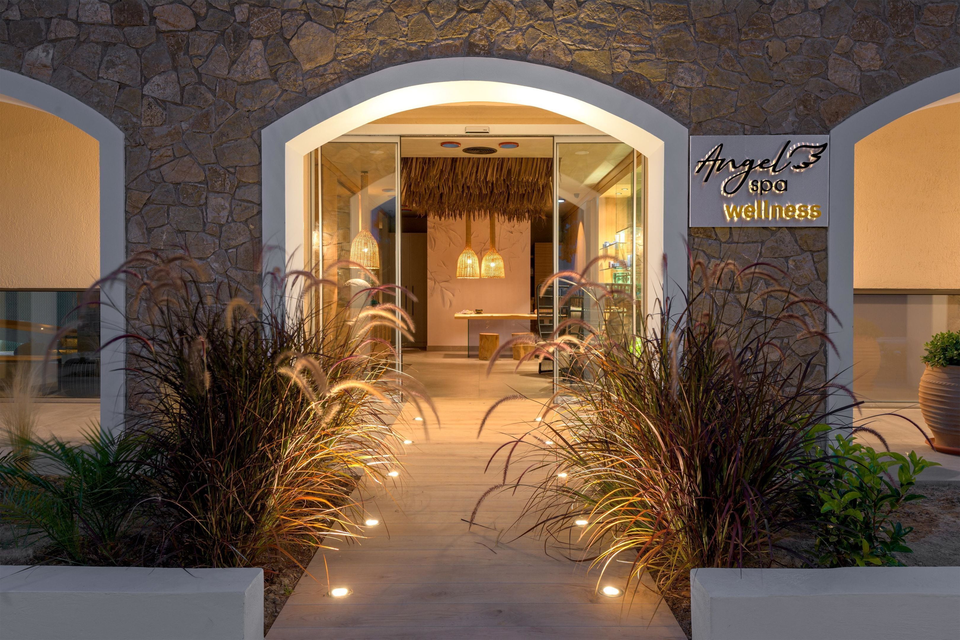 A spa entrance with a stone facade, an archway, and a sign reading "Angel Spa Wellness".