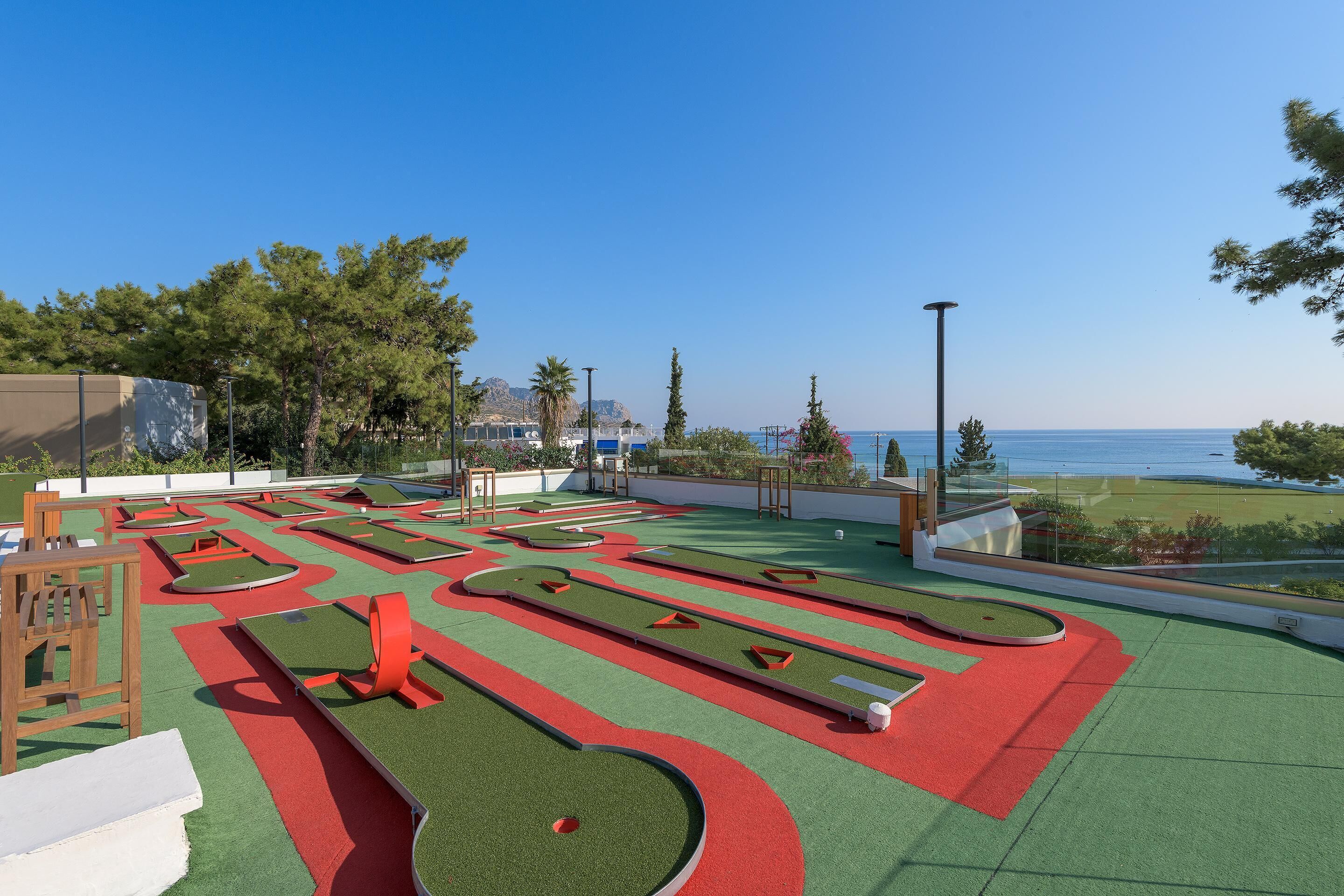 A miniature golf course with a clear view of the sea and mountains in the background.