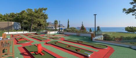 A miniature golf course with a clear view of the sea and mountains in the background.