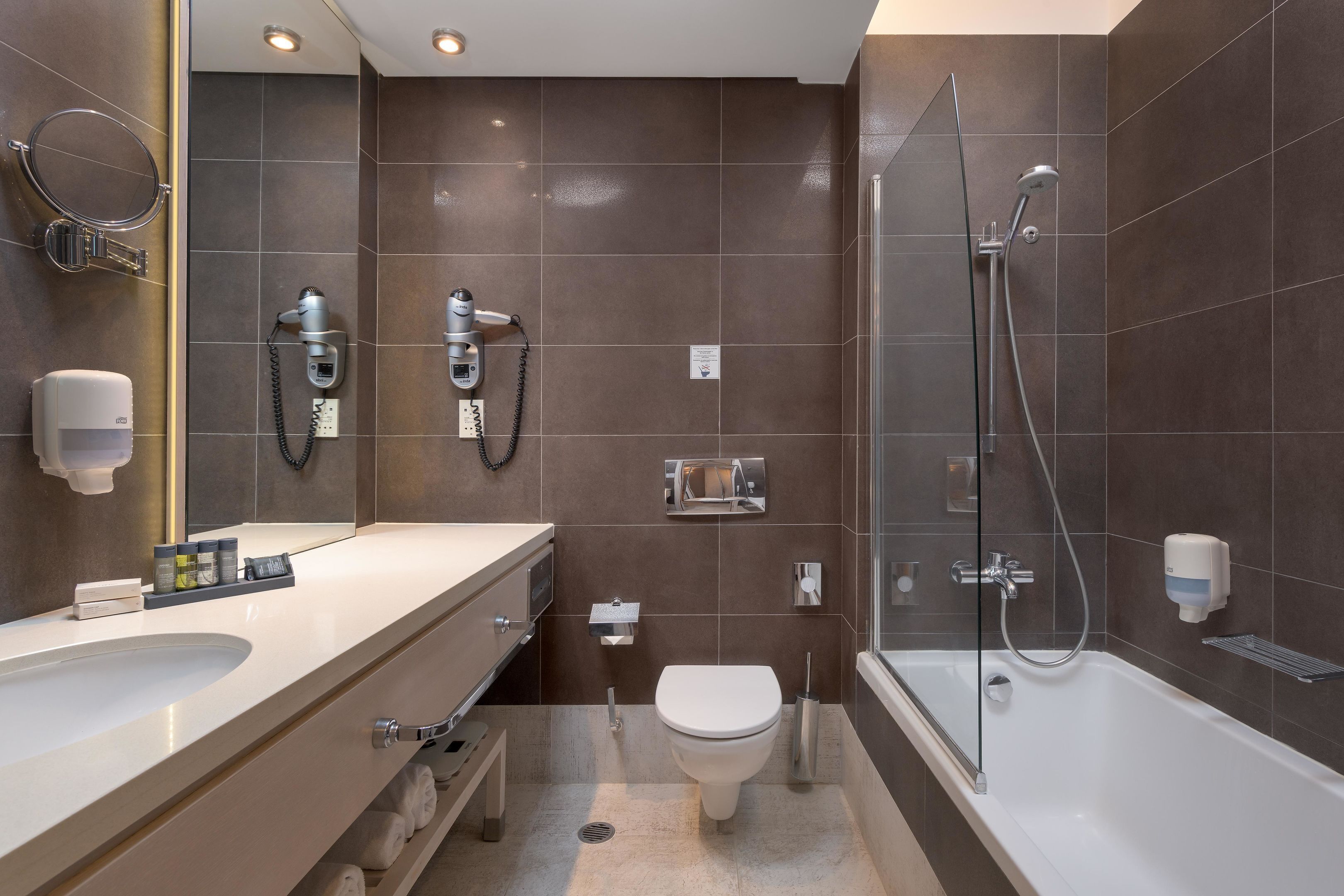 A modern bathroom with a large bathtub, a separate shower area, a toilet, and a vanity with a sink and towel rack.