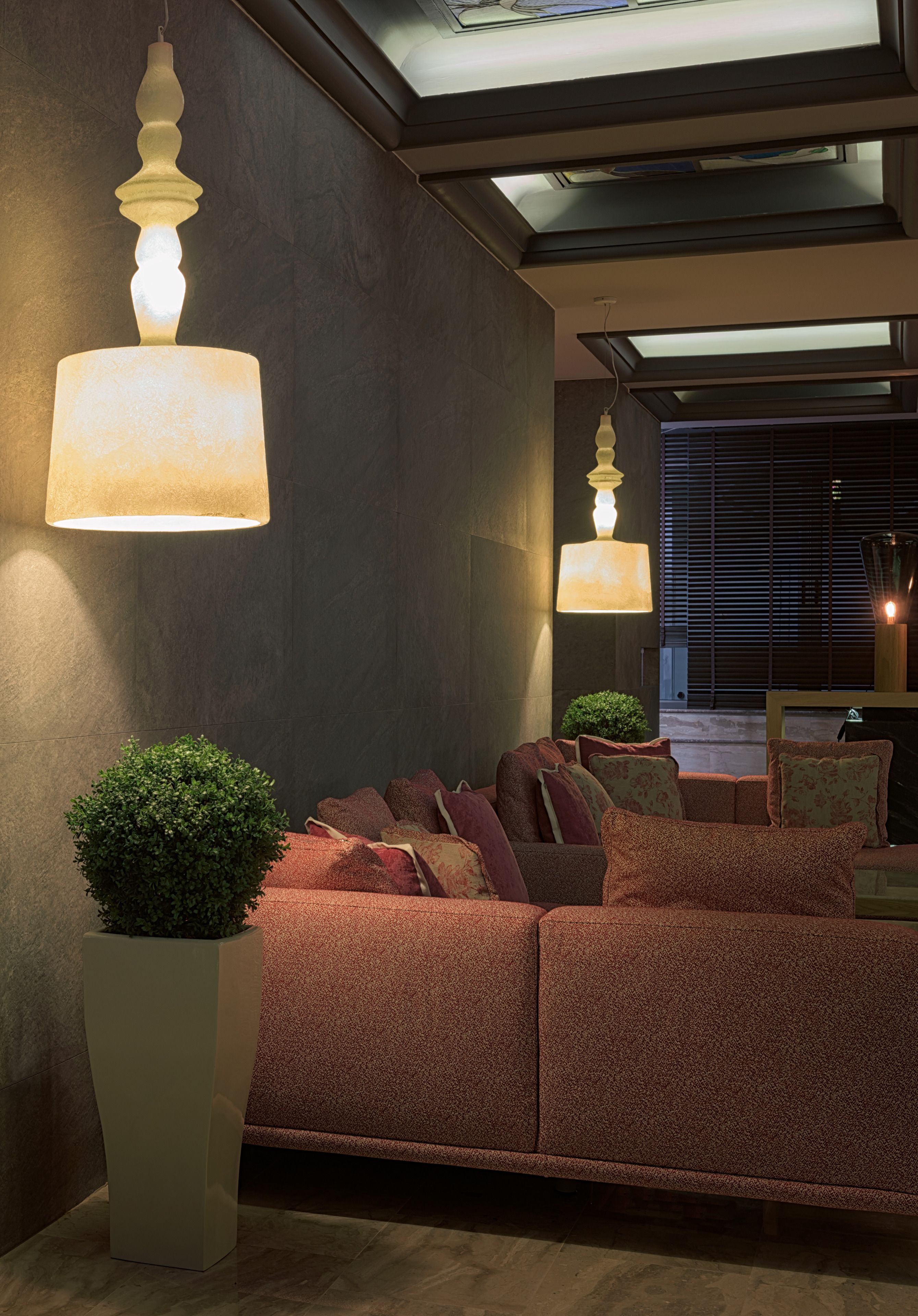 A modern interior with a sectional sofa, two floor lamps, and a potted plant.