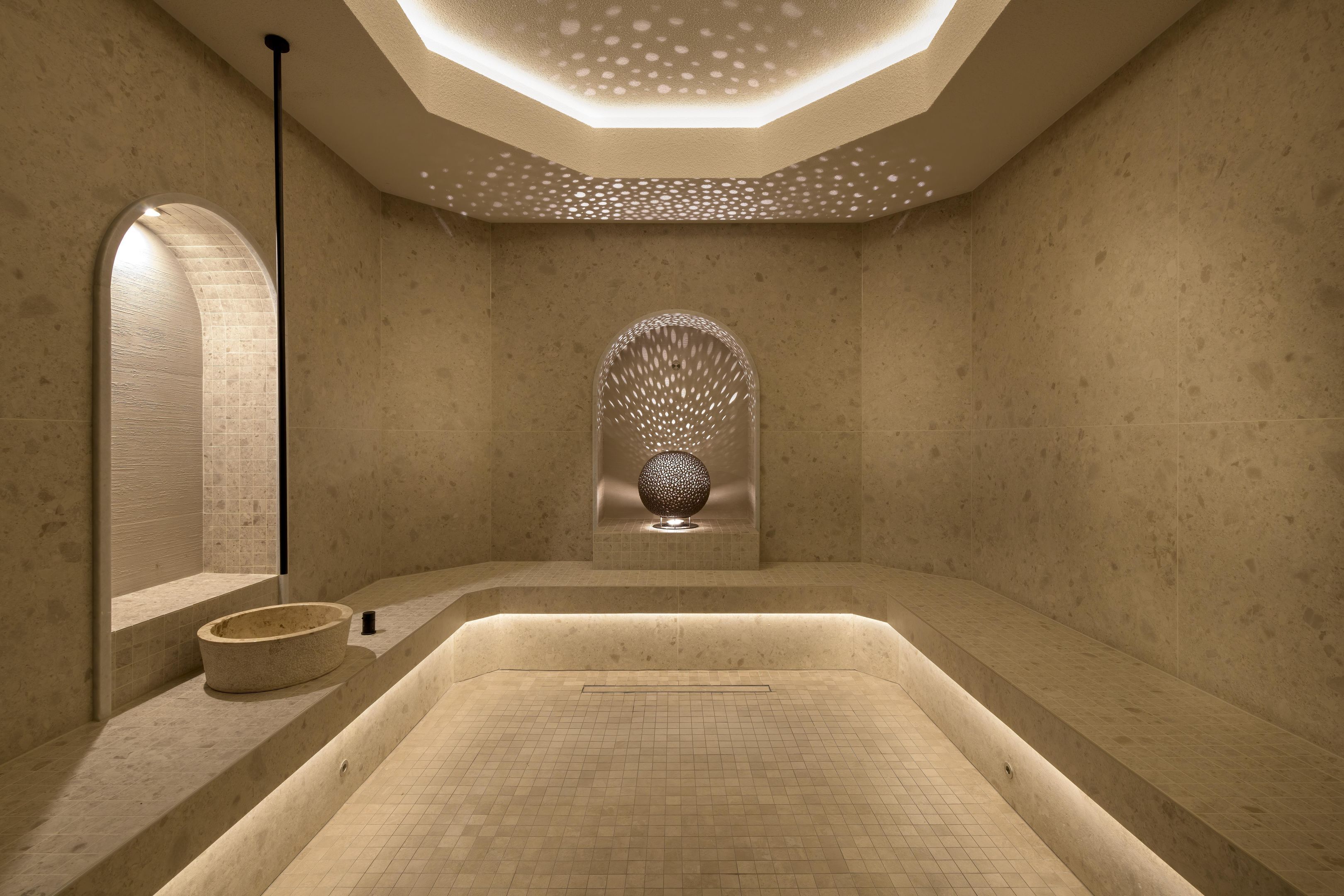 Een moderne spa-ruimte met een groot bad, een stenen wasbak en een decoratieve wandversiering.