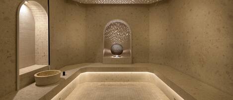 Een moderne spa-ruimte met een groot bad, een stenen wasbak en een decoratieve wandversiering.