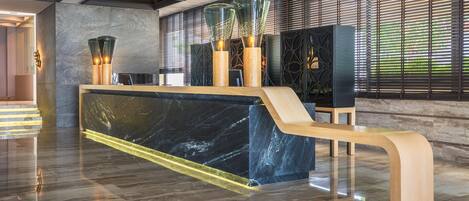 Una moderna recepción con encimera de mármol, banco de madera y lámparas de vidrio decorativas.