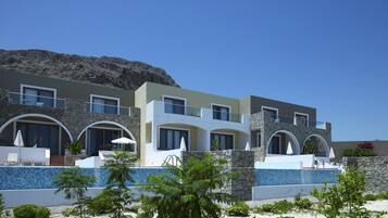 A modern multi-story hotel with stone facades, balconies, and a pool area.