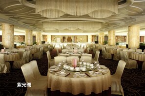 A banquet hall with round tables set for dining, large columns, and a high ceiling with decorative lighting. - Venus Royal Hotel (Shenzhen)