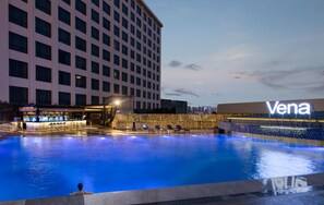 A swimming pool with lounge chairs, a bar area, and a building with the name 'Vena' visible. - Venus Royal Hotel (Shenzhen)