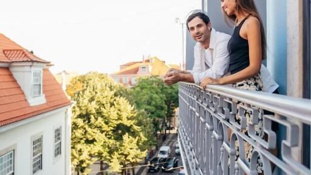 Een balkon met uitzicht op een straat met geparkeerde auto's en een zebrapad.