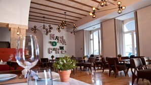 Een restaurant interieur met houten vloeren, moderne hanglampen en een muur met de tekst 'MARIA DO CARO'.