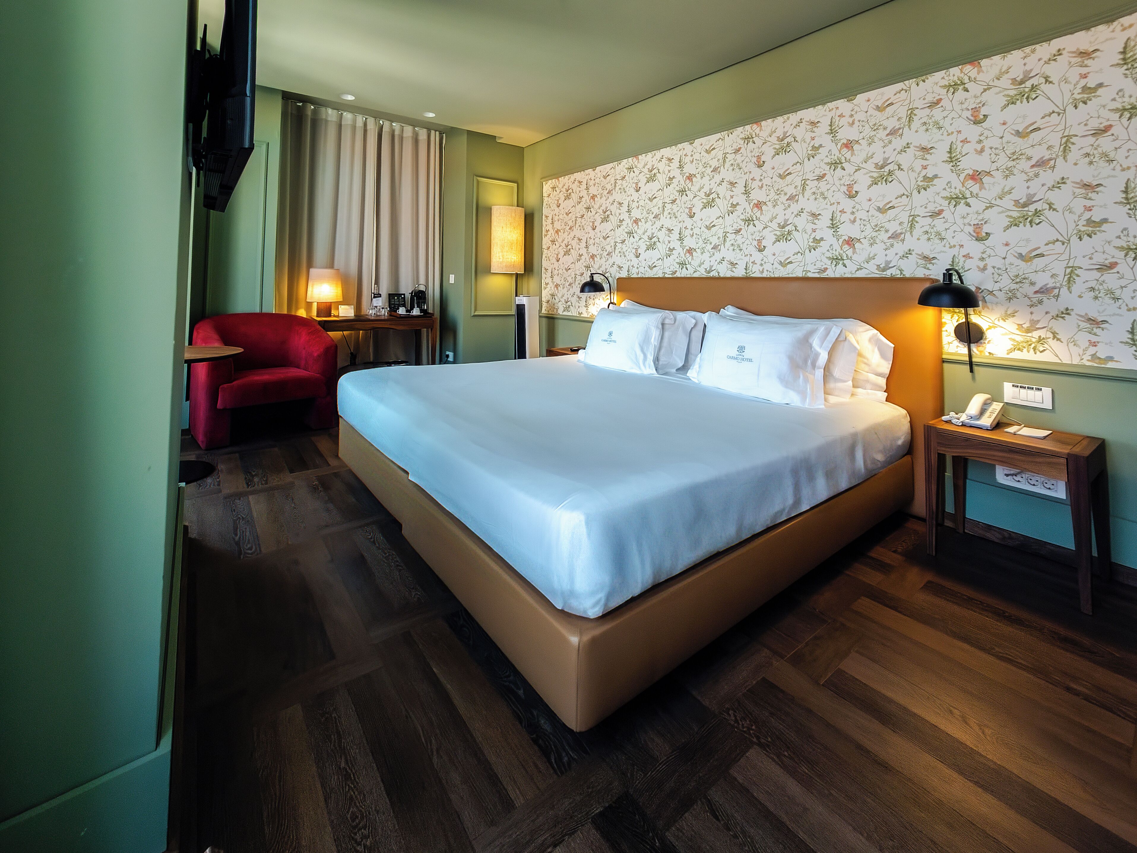 Habitación de hotel con una cama grande, un escritorio con silla, un teléfono y una lámpara.