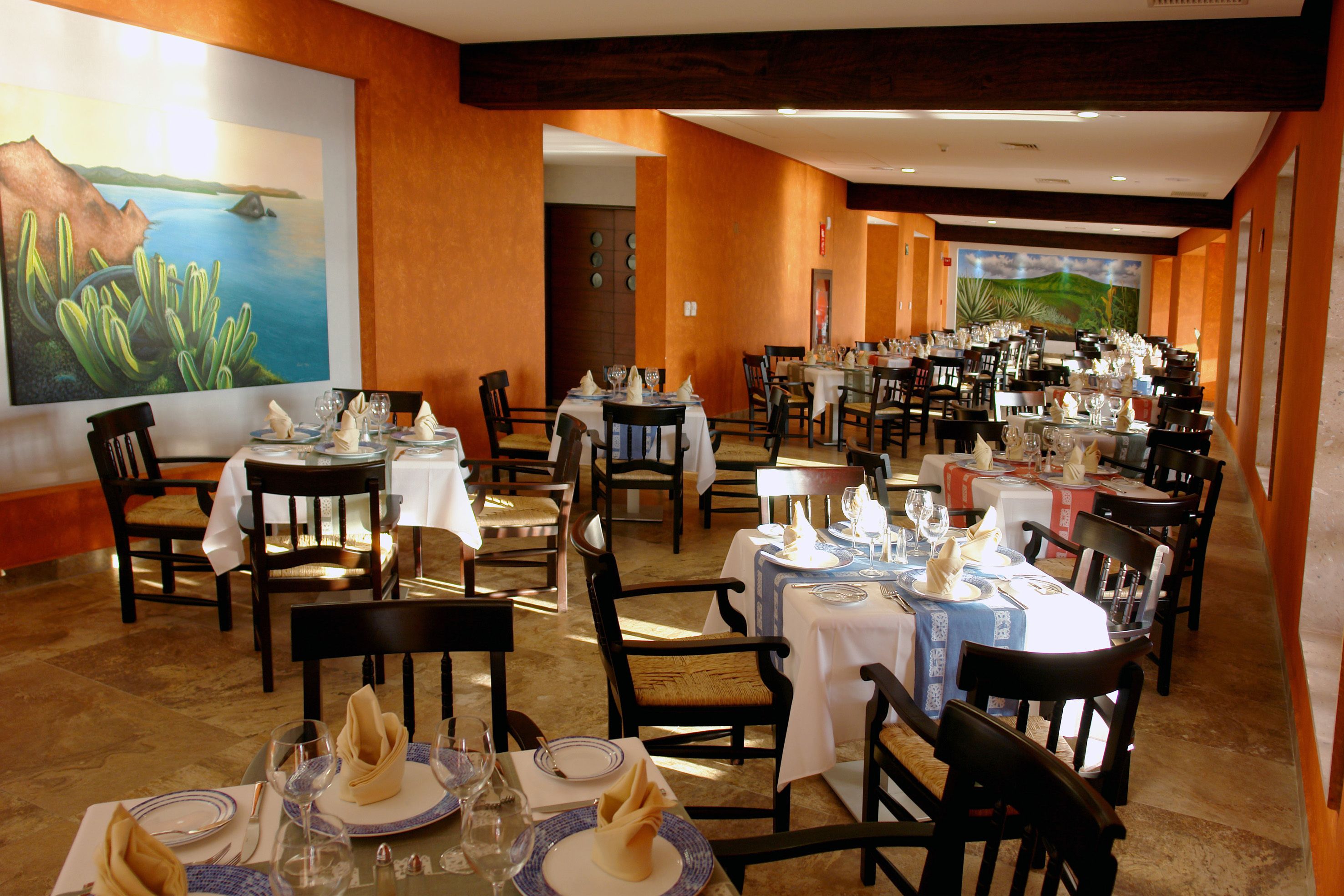 A restaurant with multiple tables set for dining, featuring a variety of chairs and tables.