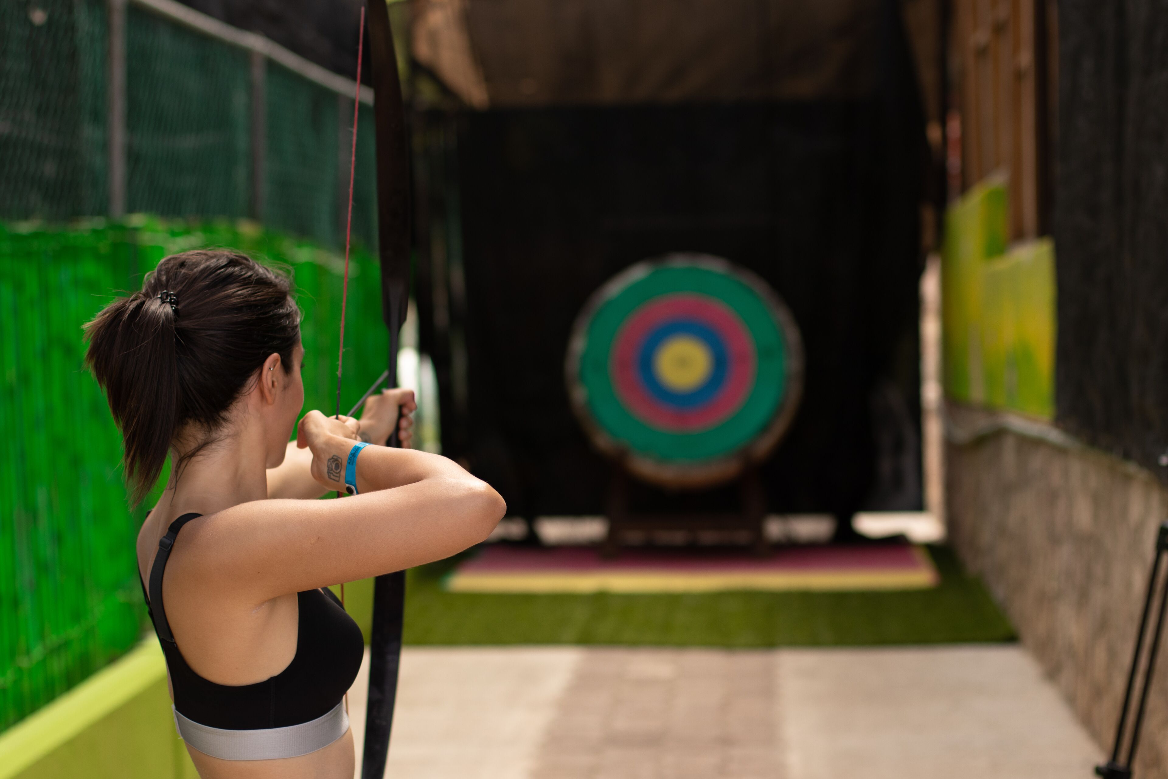 A person aiming an arrow at a target in an indoor facility.