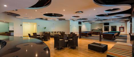 A modern lounge with a pool table, comfortable seating, and a unique ceiling design.