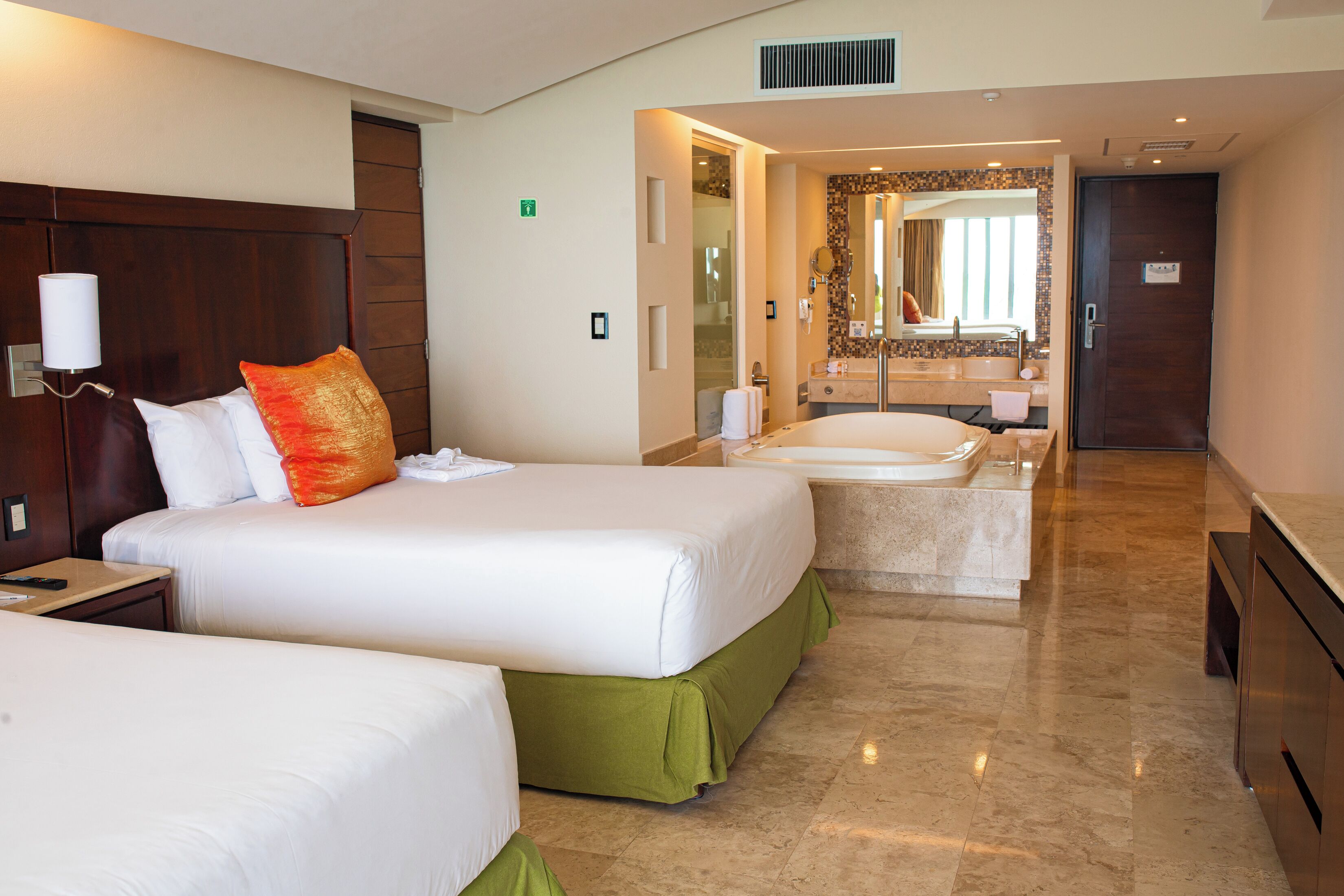 A hotel room with two beds, a bathroom with a bathtub, and a separate shower area.